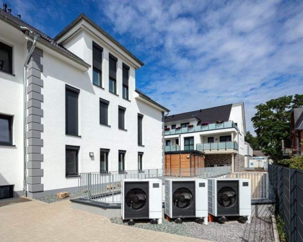 Image d'une grande maison neuve avec devant trois 3 pompes à chaleur en cascade mises en place par l'entreprise Suisse AFM